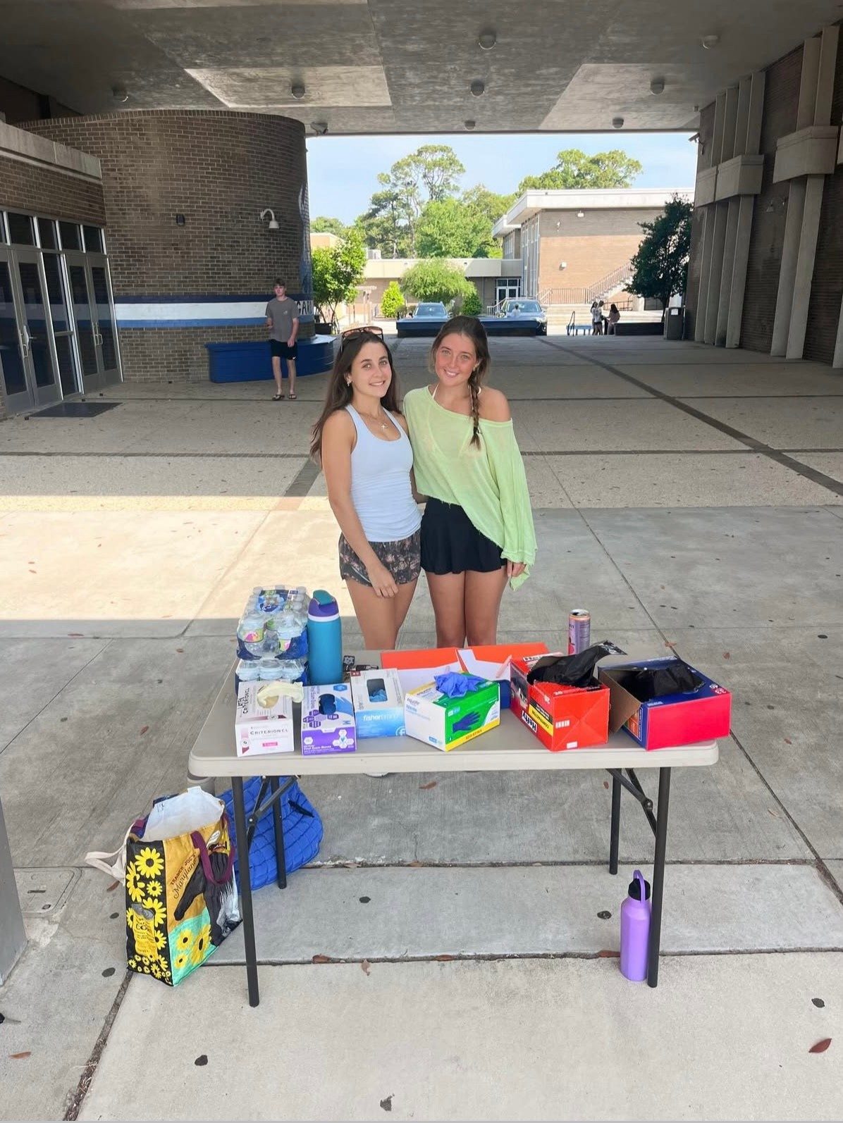 Two Hoggard IB students running a donation drive table outside the school